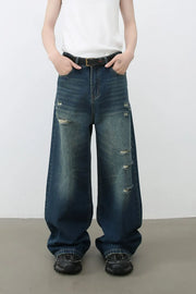 Distressed baggy dark wash denim jeans with wide legs and ripped details.