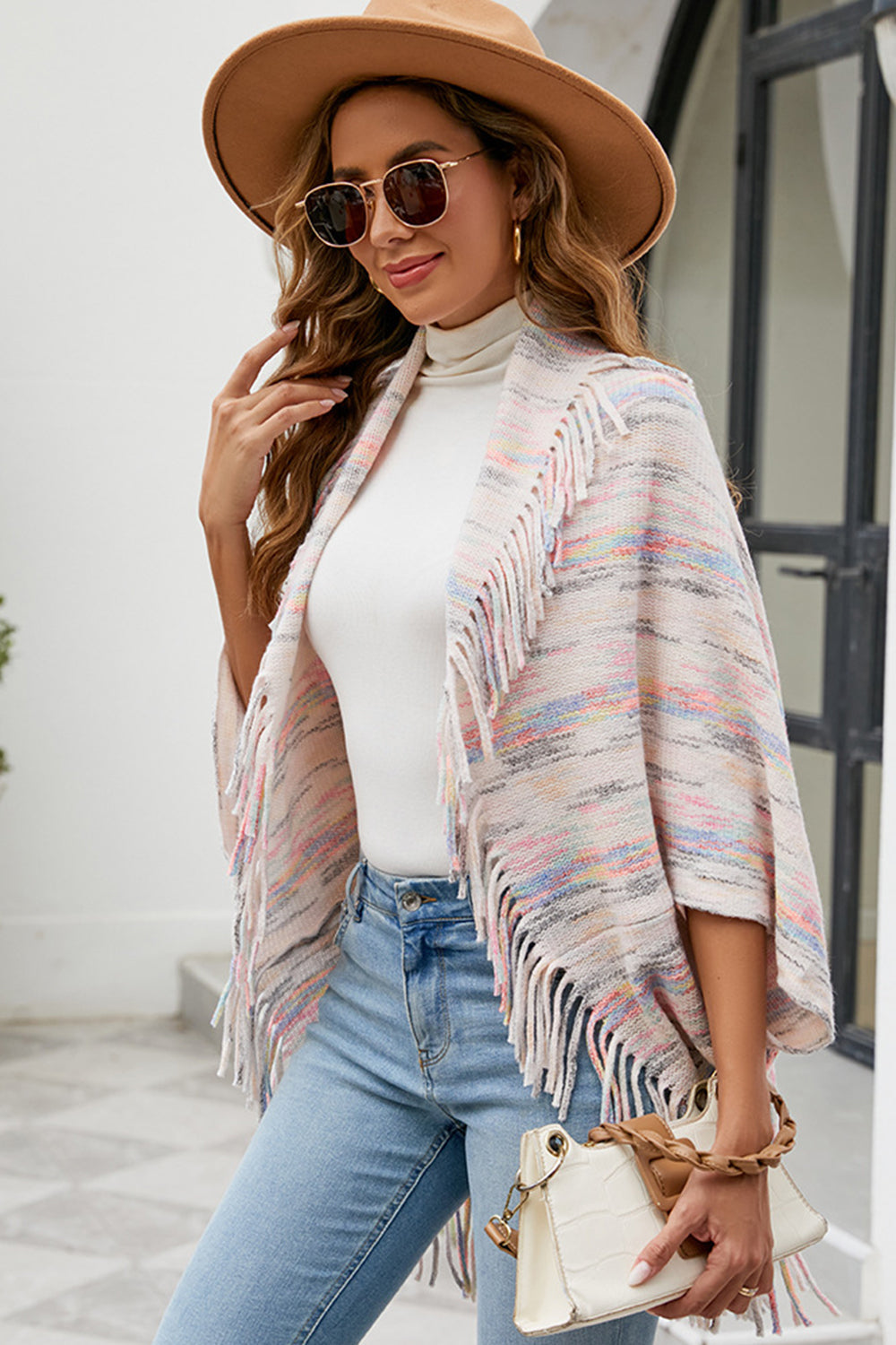 Textured knit cape with fringe trim in a multi-color stripe pattern, open front, and cloak sleeves.