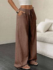 Brown crinkled wide-leg drawstring pants with pockets and a relaxed fit.