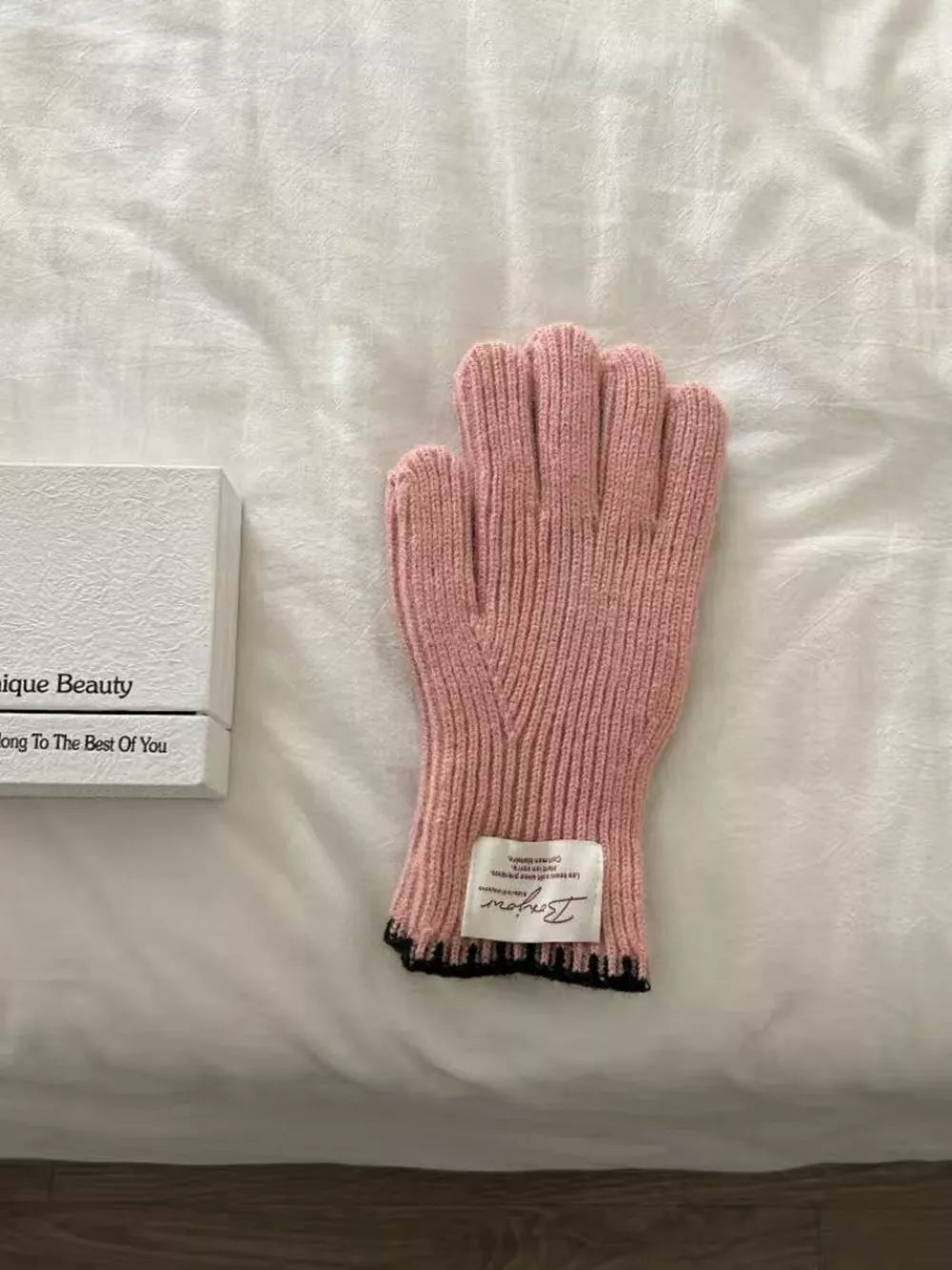 Pink ribbed knit gloves with scalloped black cuff detail and label