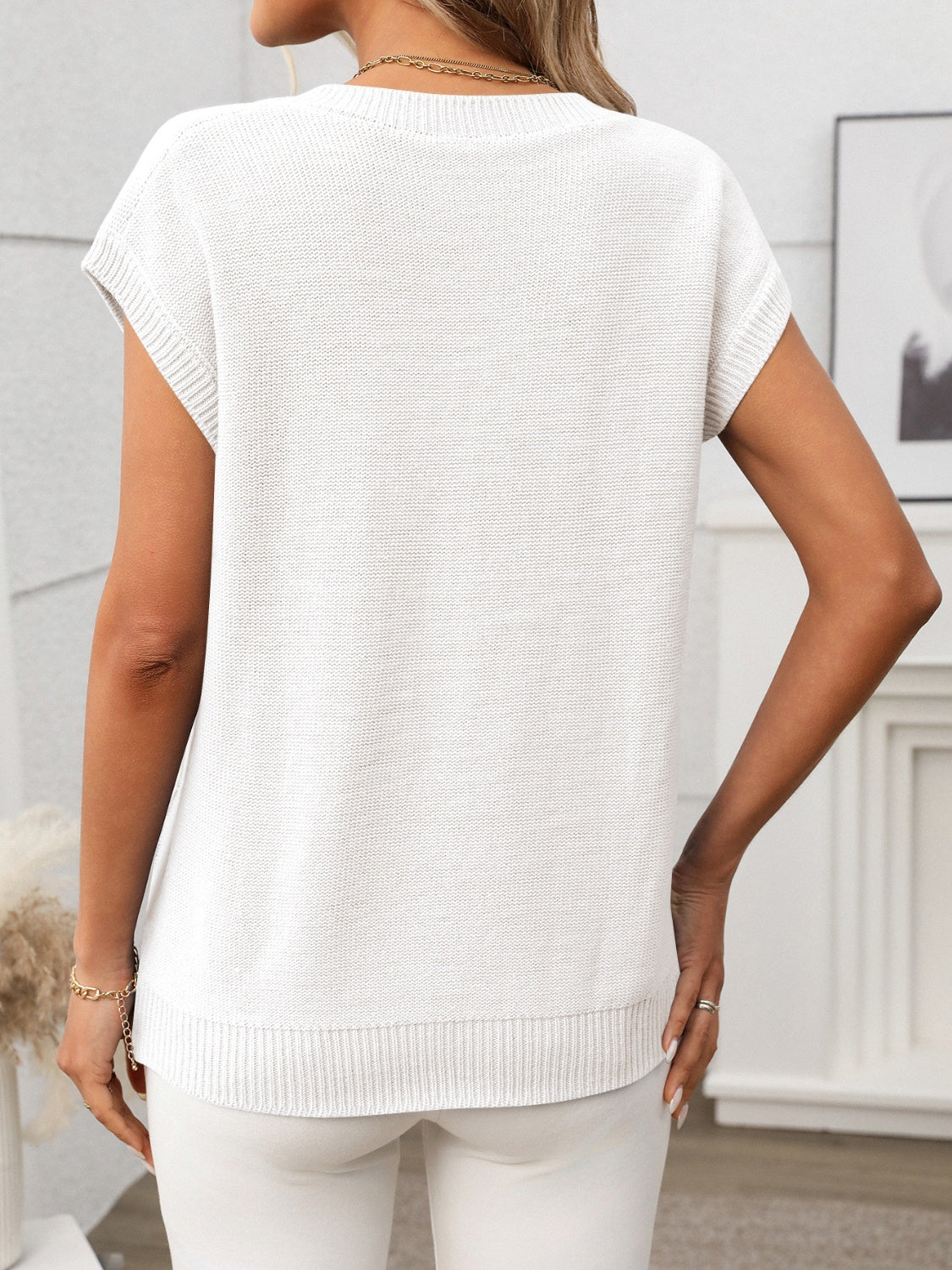White cable knit V-neck vest with short sleeves and ribbed trim.