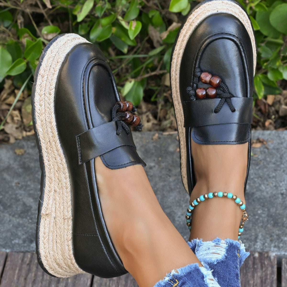 Black espadrille wedge slip-on loafers with braided jute sole and beaded tassel detail.