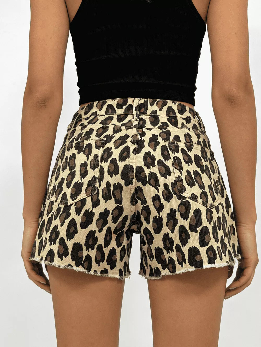 Leopard print high-waisted denim shorts with raw hem and button closure.