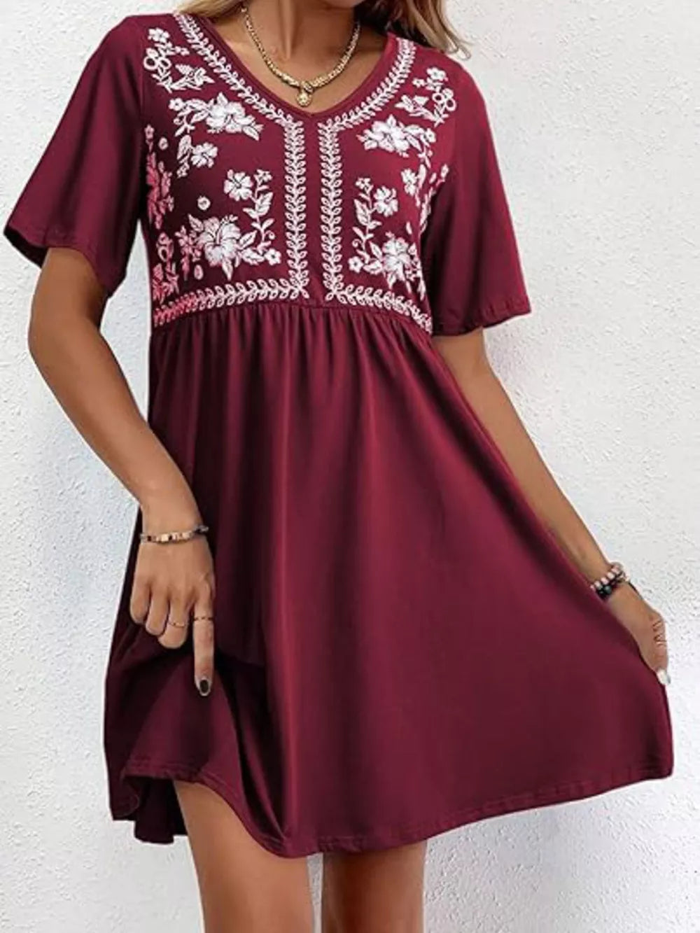 Burgundy embroidered floral v-neck mini dress with short sleeves and a gathered waist.