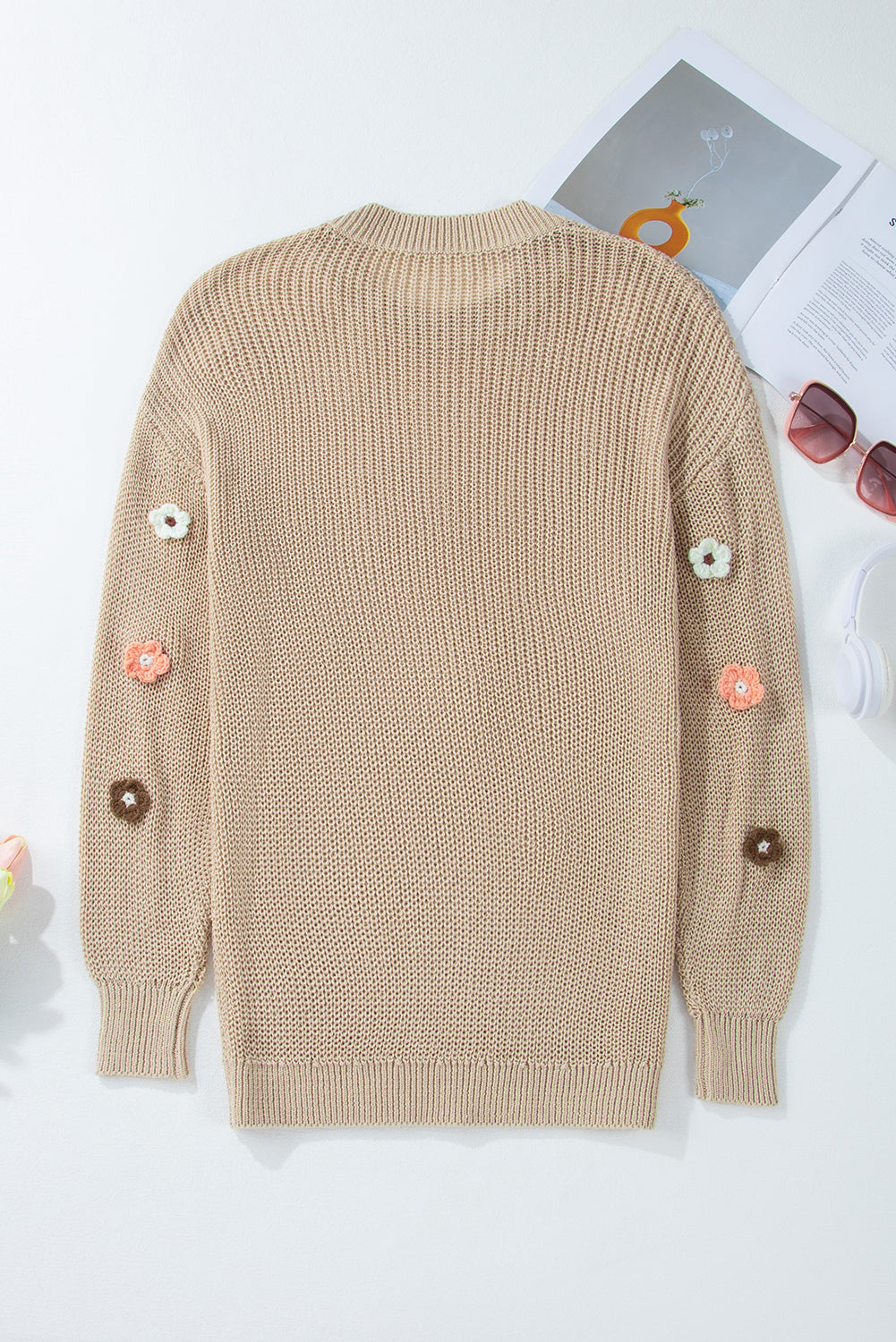 Khaki knit sweater with embroidered floral details on the sleeves.