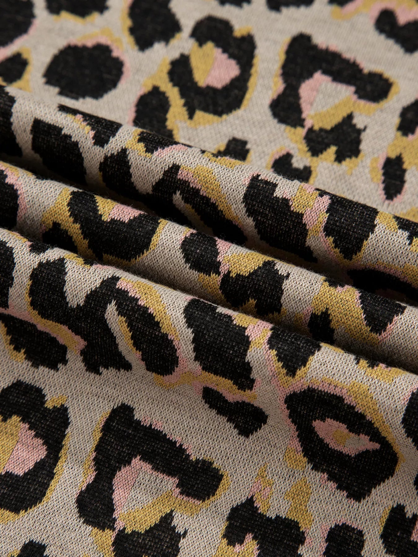Cozy leopard print loungewear fabric with black, pink, and yellow spots on a tan background.