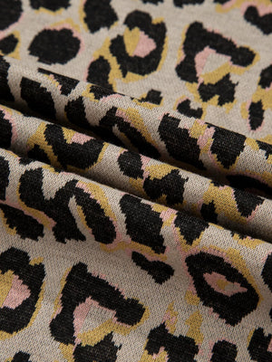 Cozy leopard print loungewear fabric with black, pink, and yellow spots on a tan background.