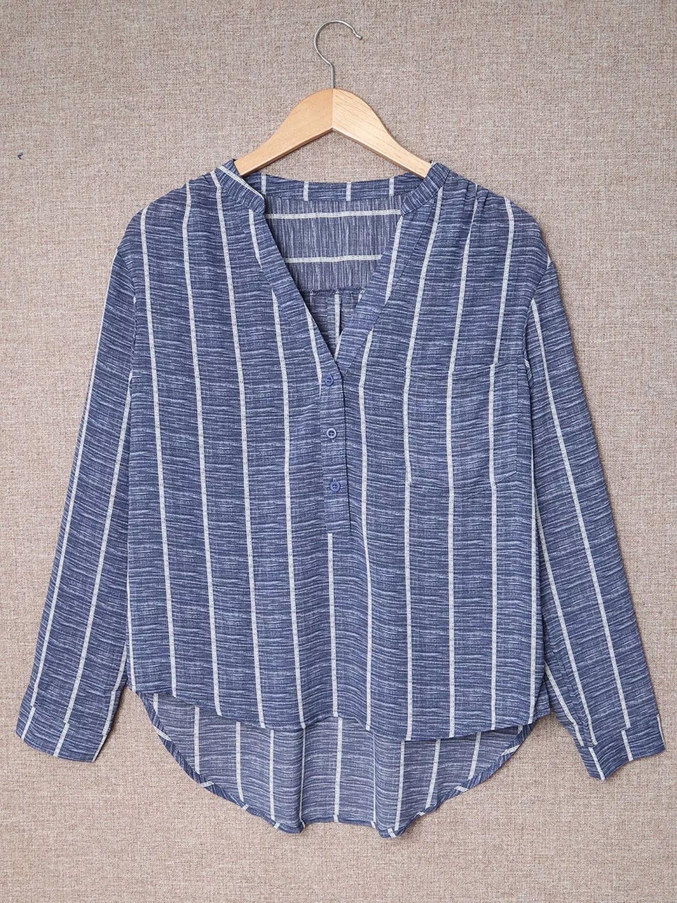 Dusty blue striped V-neck buttoned blouse with long sleeves and a curved hem.