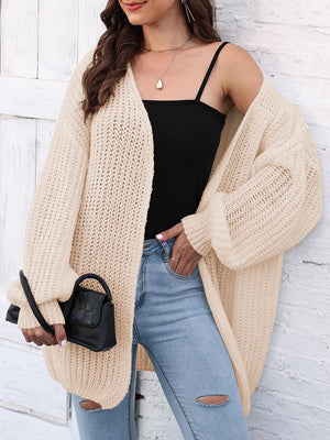 Beige balloon sleeve open knit cardigan with a relaxed fit, styled with a black top and jeans.