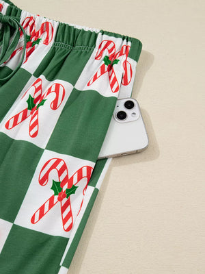 Green checkered pajama pants with candy cane print and side pocket holding a phone
