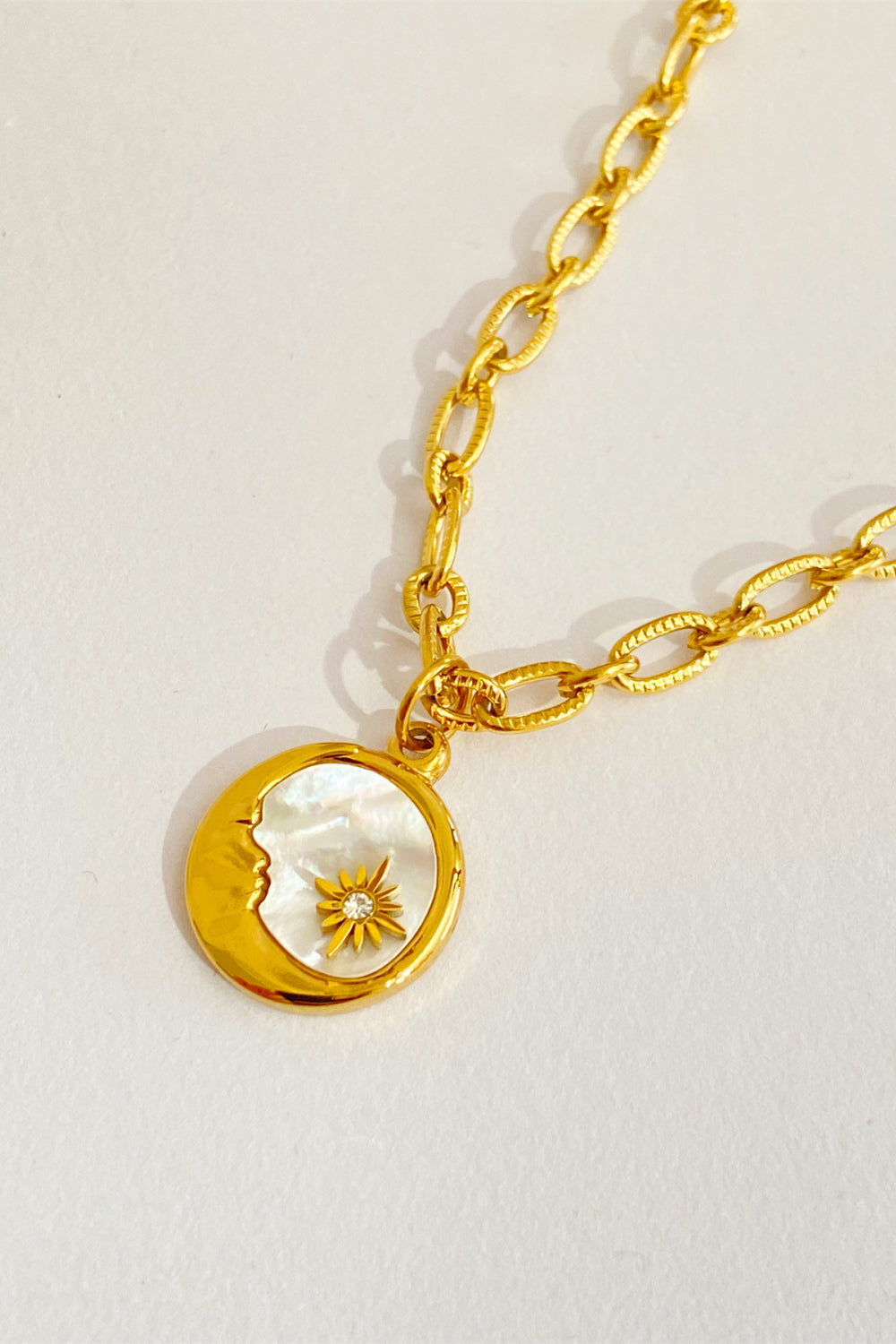 Celestial charm necklace in 18K gold-plated metal with a moon and sun charm.