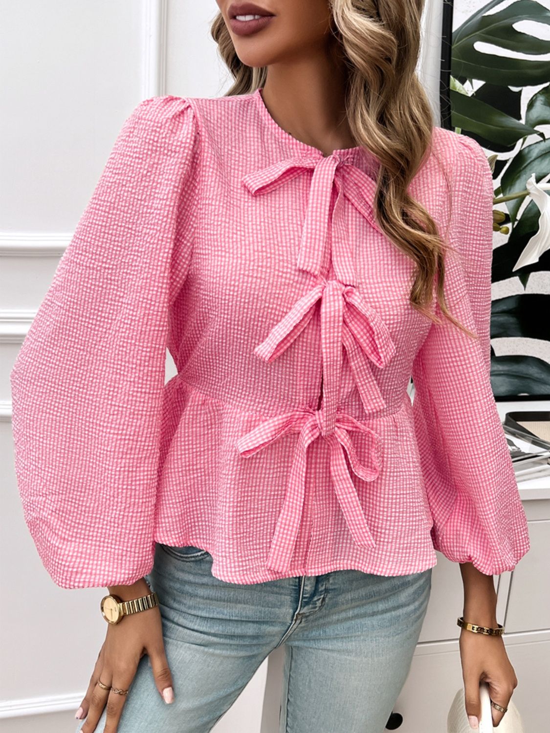Pink textured peplum blouse with puff sleeves and multiple bow details.