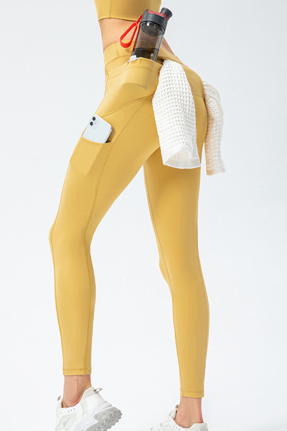 Gold athletic leggings with utility pockets, phone pocket, and towel detail.