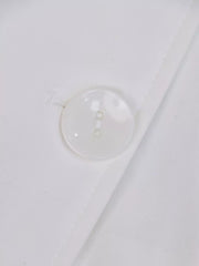 White midi dress with lapel collar, cuffed sleeves, and tie-waist detail, shown with a button closure.