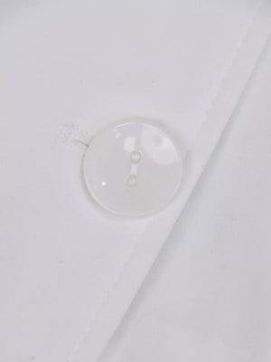 White midi dress with lapel collar, cuffed sleeves, and tie-waist detail, shown with a button closure.