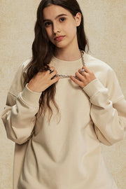 Oversized tan crewneck sweatshirt with subtle shoulders and ribbed cuffs.