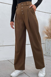 Brown high-waisted tailored wide-leg trousers with button detail and pleats.