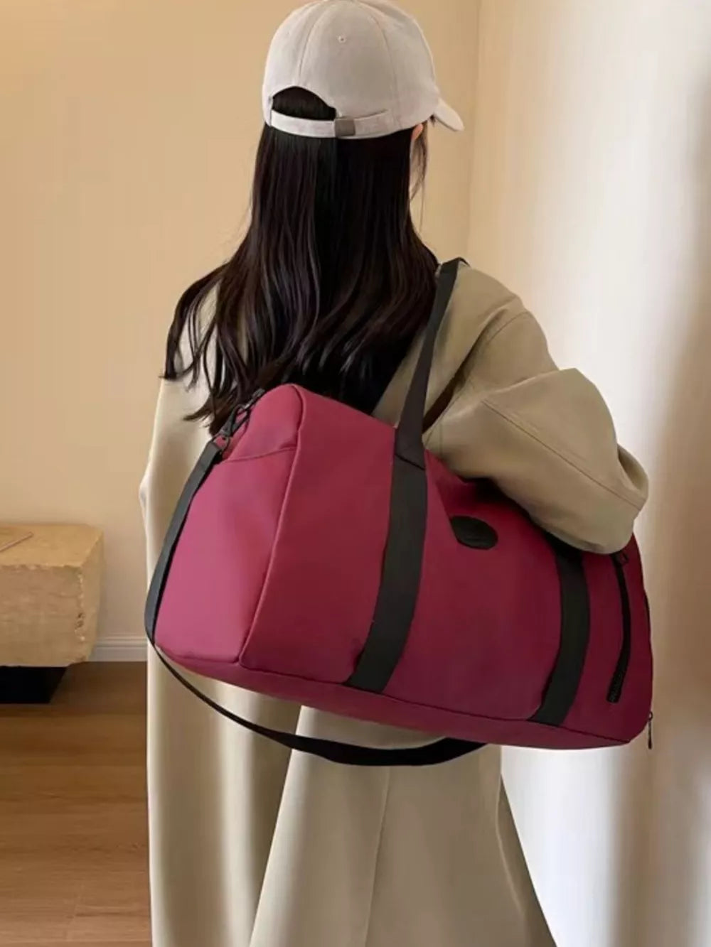 Wine red travel bag with adjustable straps and black accents, worn over the shoulder.