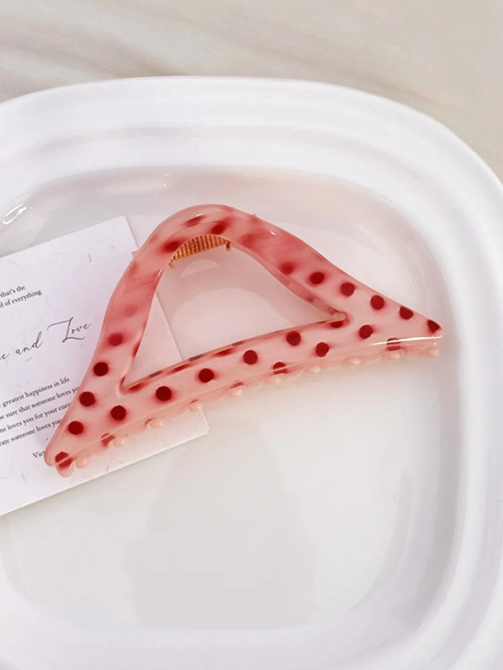 Polka dot claw hair clip in Style A, a pink triangular clip with red dots.