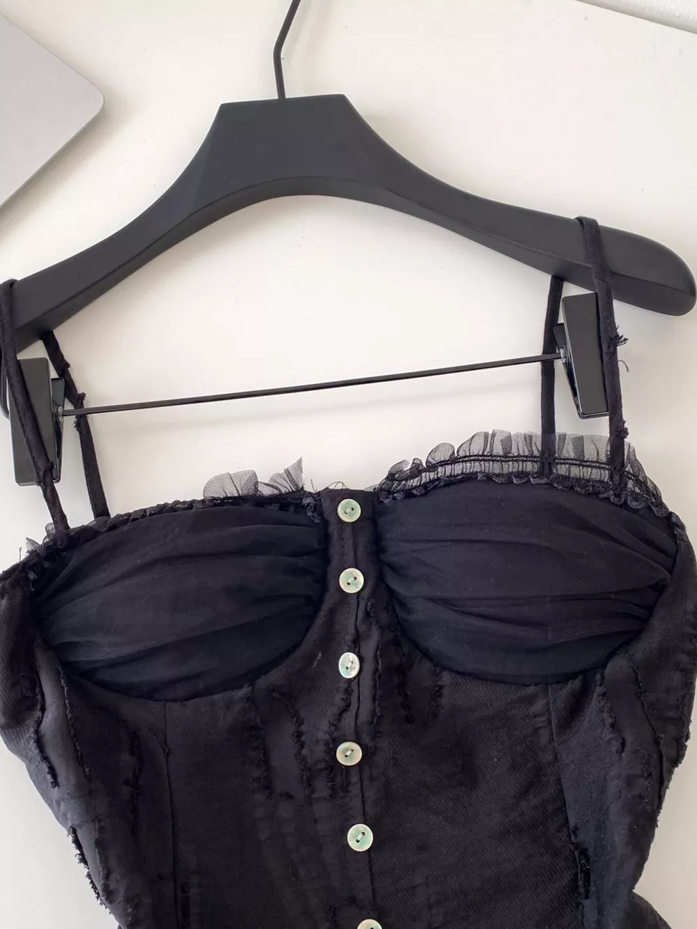 Black lace ruffle hem tank top with button front and sheer bust detail.