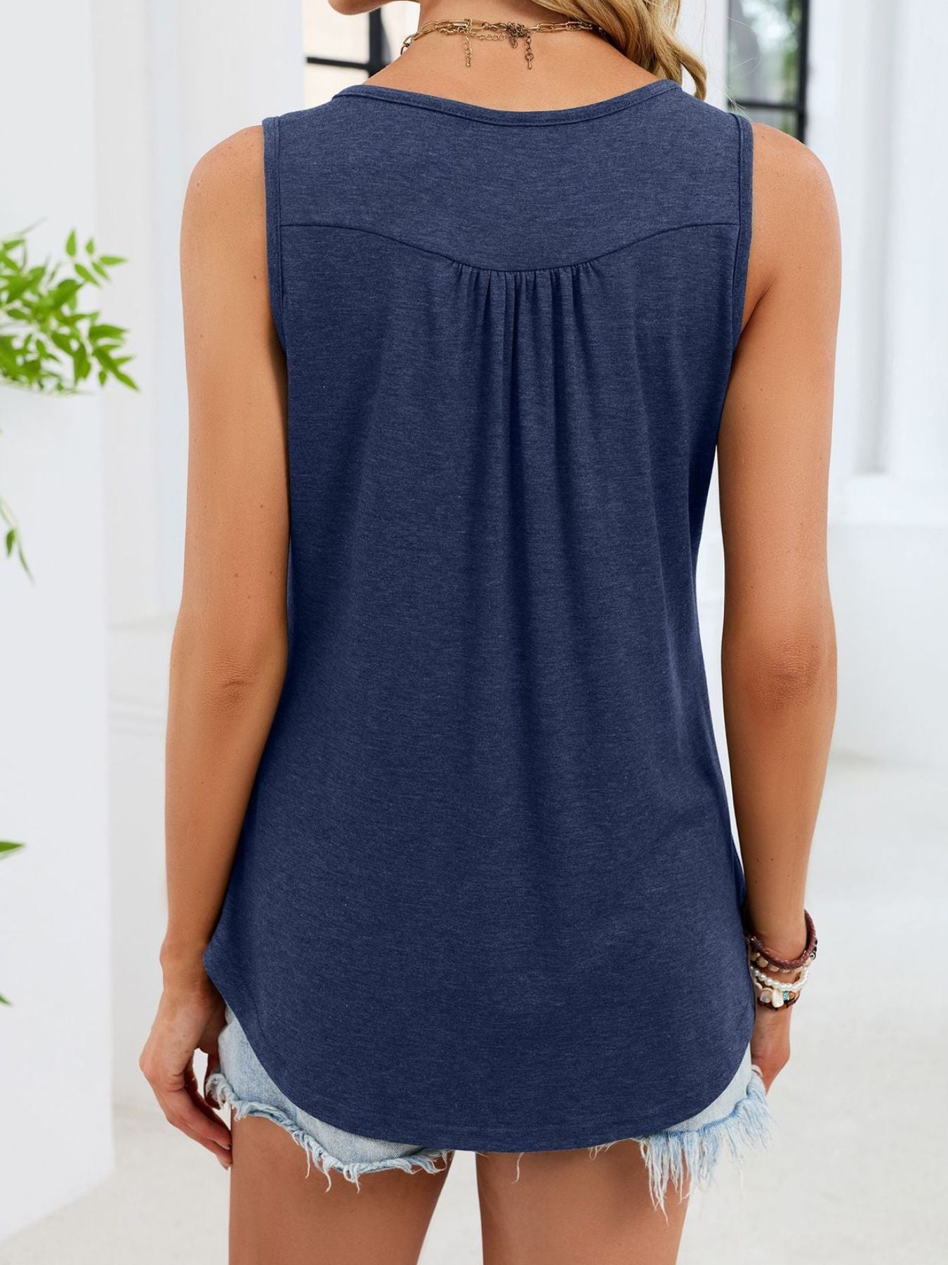 Navy blue ruched tank top with button detail and curved hem.