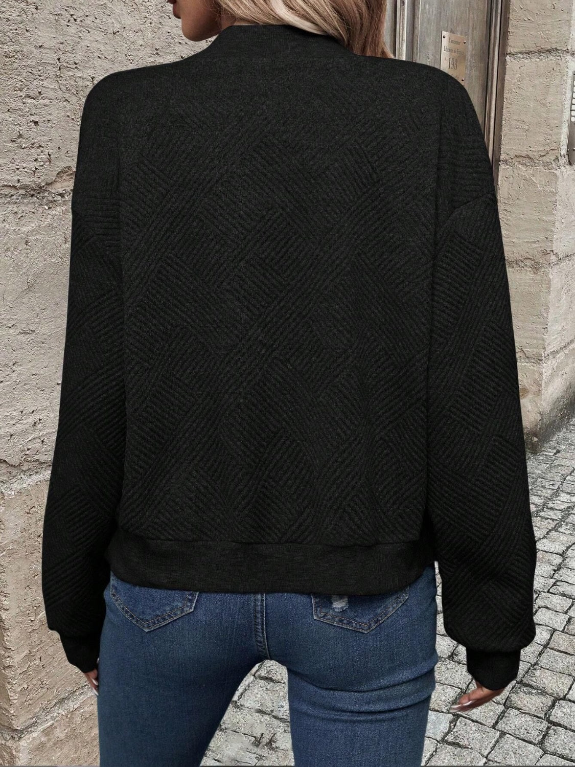 Black geometric quilted bomber jacket with a mock neck and ribbed cuffs.
