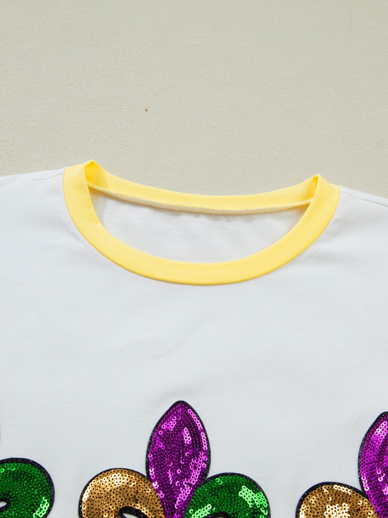 White cotton t-shirt with yellow trim and Mardi Gras sequin design.