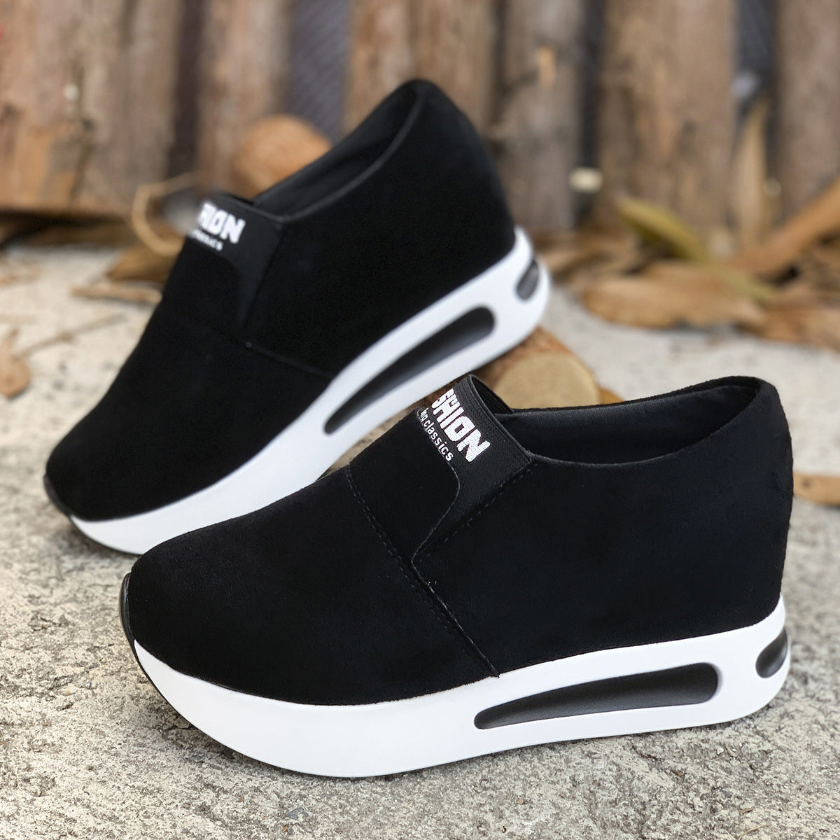 Black round toe platform slip-on sneakers with white soles and air cushioning.