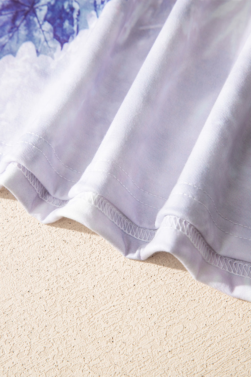 Tunic tee with faded blue and white abstract print, crew neck, and visible stitching detail.