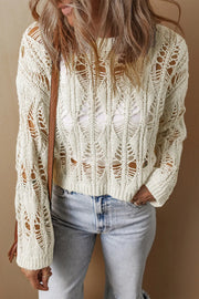 Ivory open-knit crochet crop sweater with a diamond pattern and a white tank top underneath.