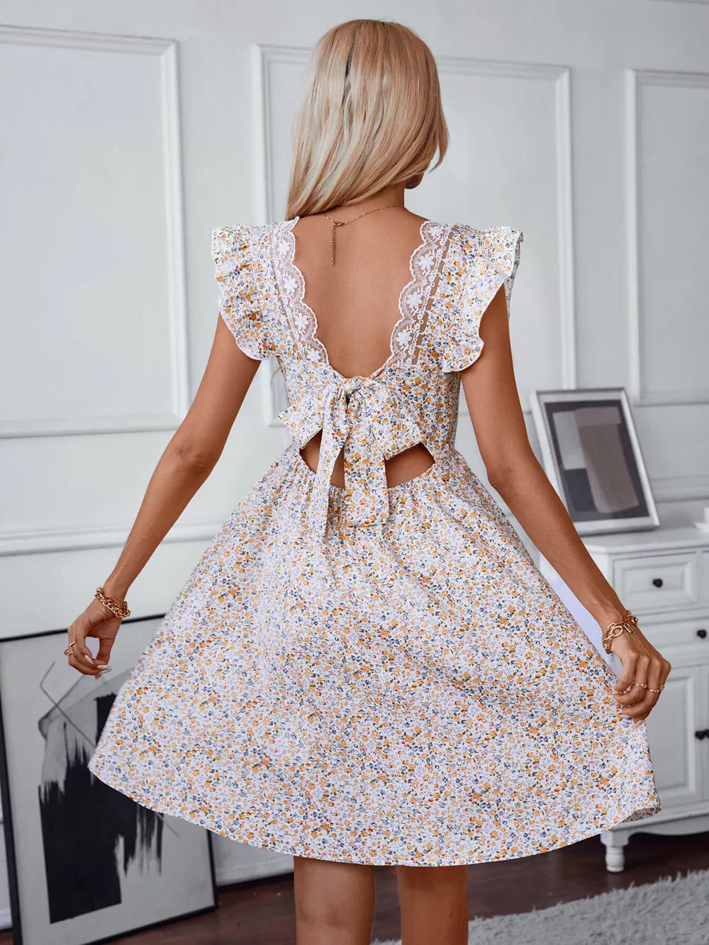 Ditsy floral mini dress with ruffled sleeves, lace trim, open back and tie detail.