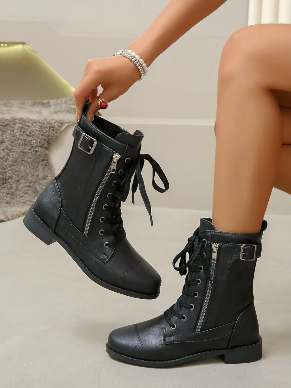 Black combat boots with side zipper detail and buckle strap.