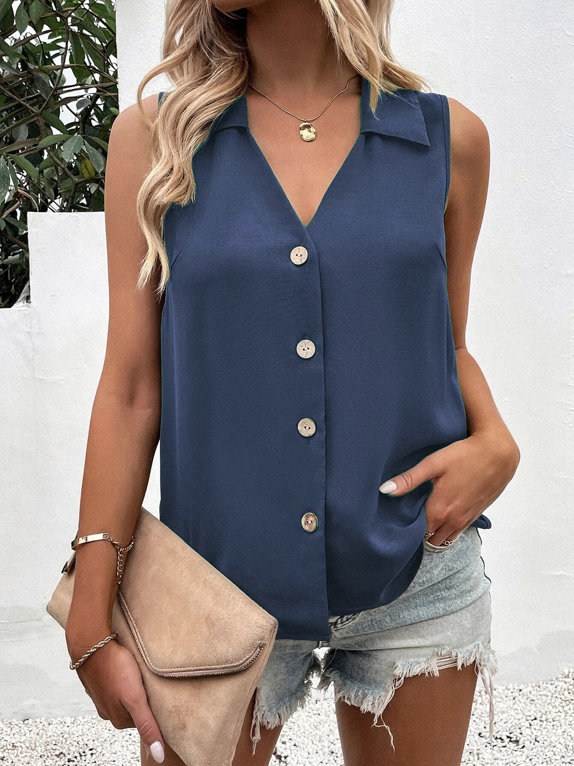 Dusty blue button-down collared sleeveless blouse with v-neck and pearl buttons