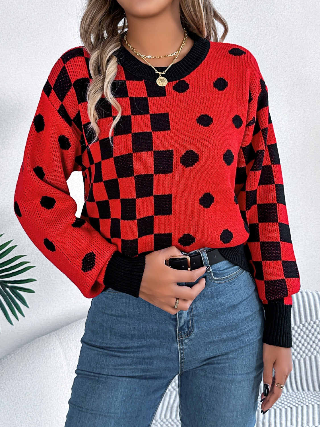 Red checkerboard and dot intarsia knit sweater with black trim and crew neck.