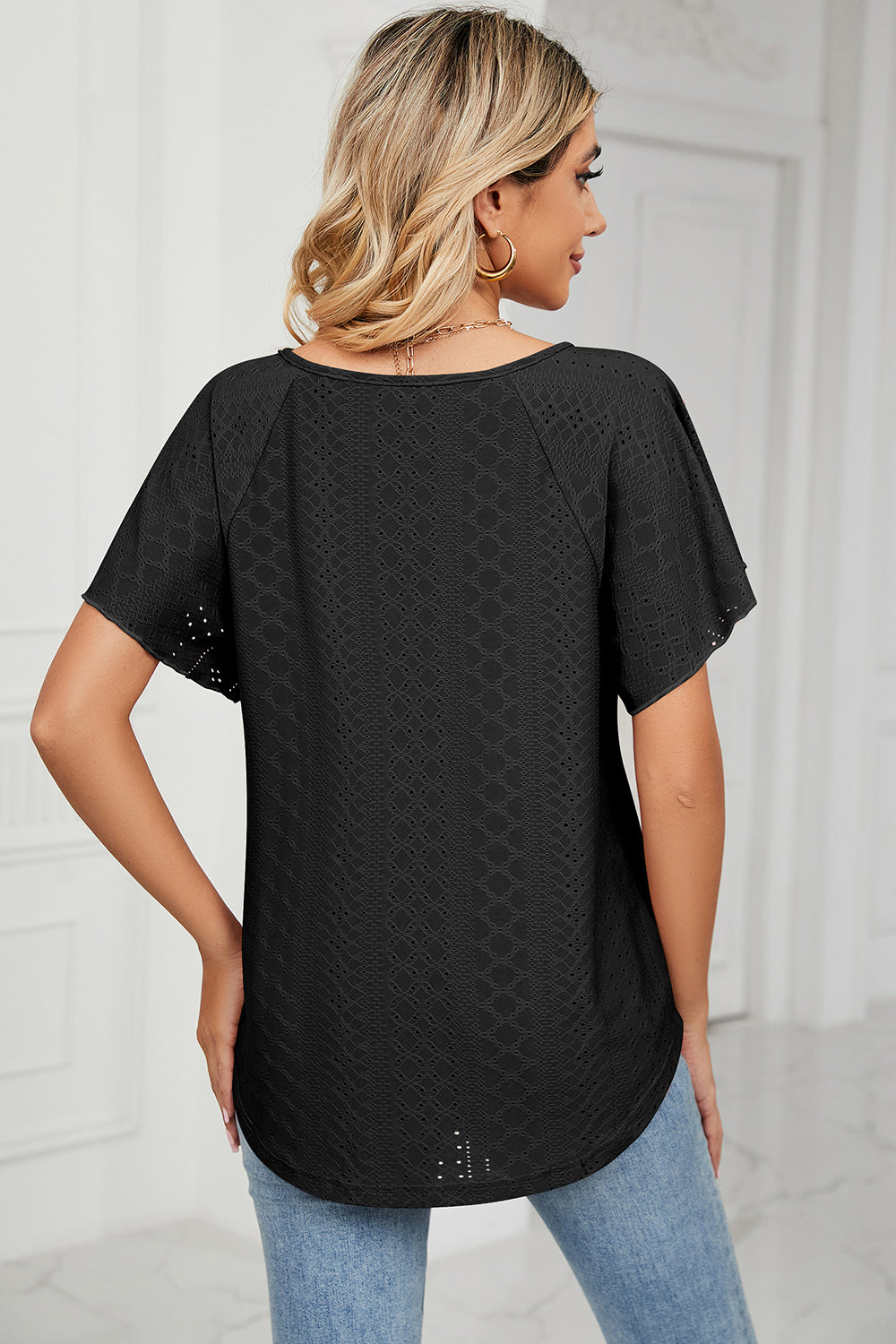 Black eyelet blouse with flutter sleeves and scoop neck, detailed texture.