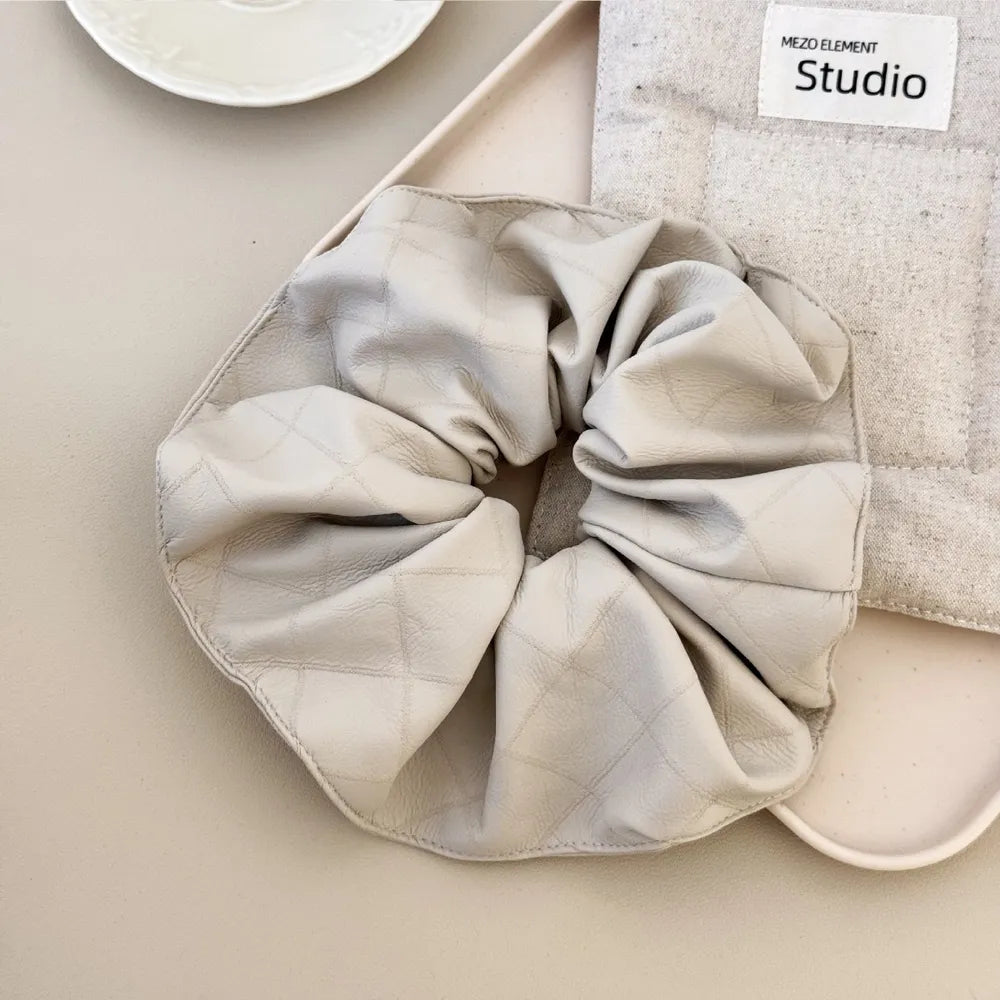 Quilted faux leather scrunchie in beige with diamond stitching detail.