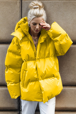 Yellow oversized puffer jacket with hood and zipper closure, casual style.
