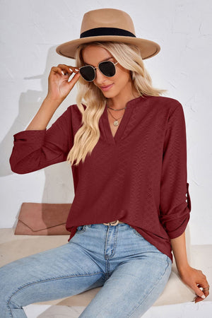 Burgundy textured henley blouse with rolled sleeves and a split neckline.