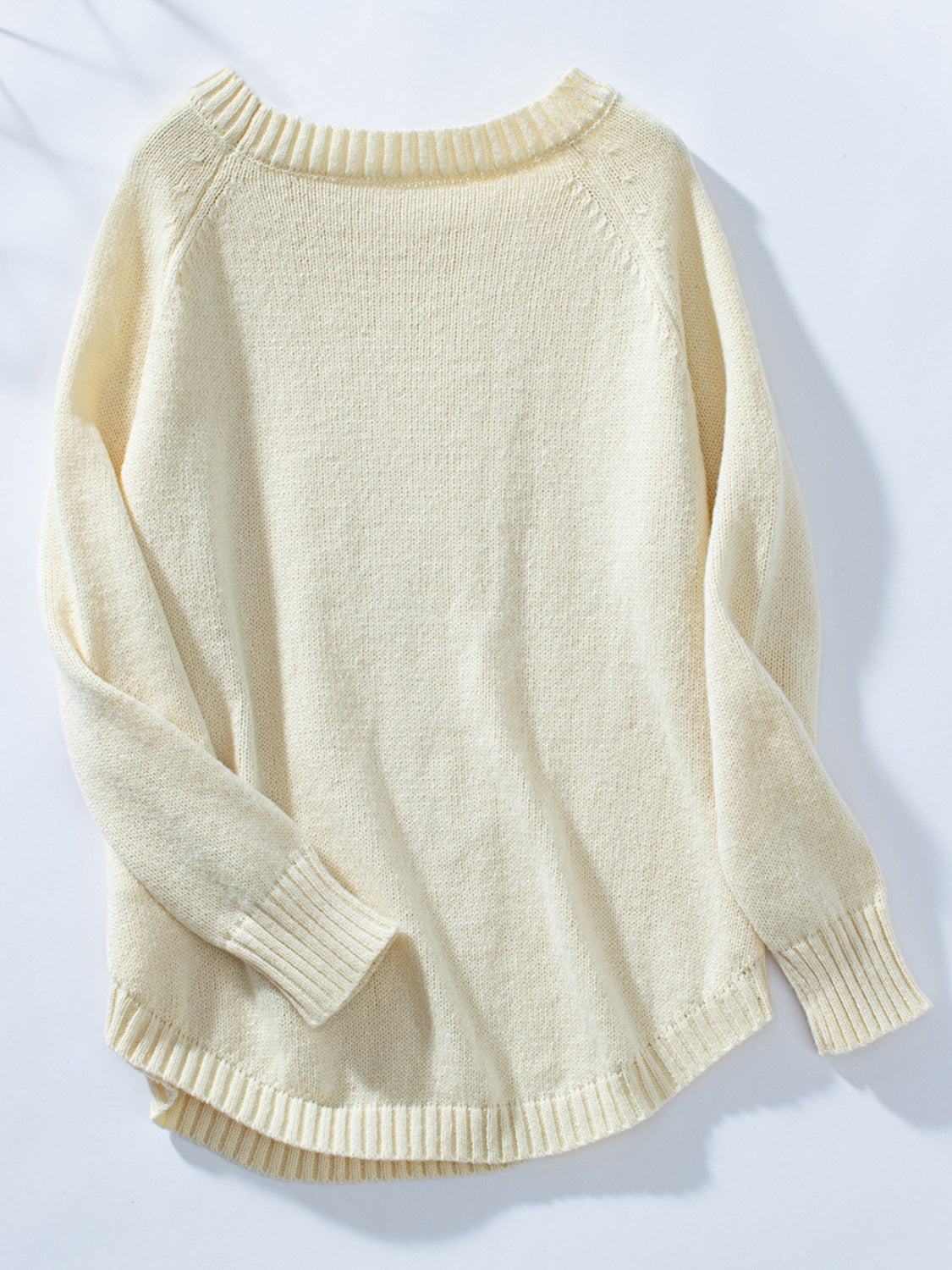 Cream acrylic cable knit sweater with button shoulder detail and raglan sleeves.