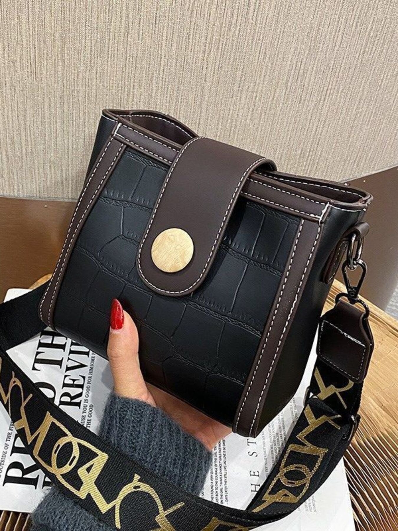 Black crocodile pattern mini crossbody bag with brown trim and gold button closure.