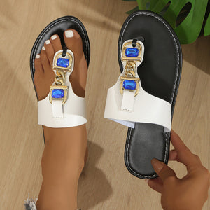 White thong sandals with gold chain and blue rhinestone embellishments.