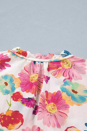 White cotton blend shirt with vibrant floral print and ruffled neckline.