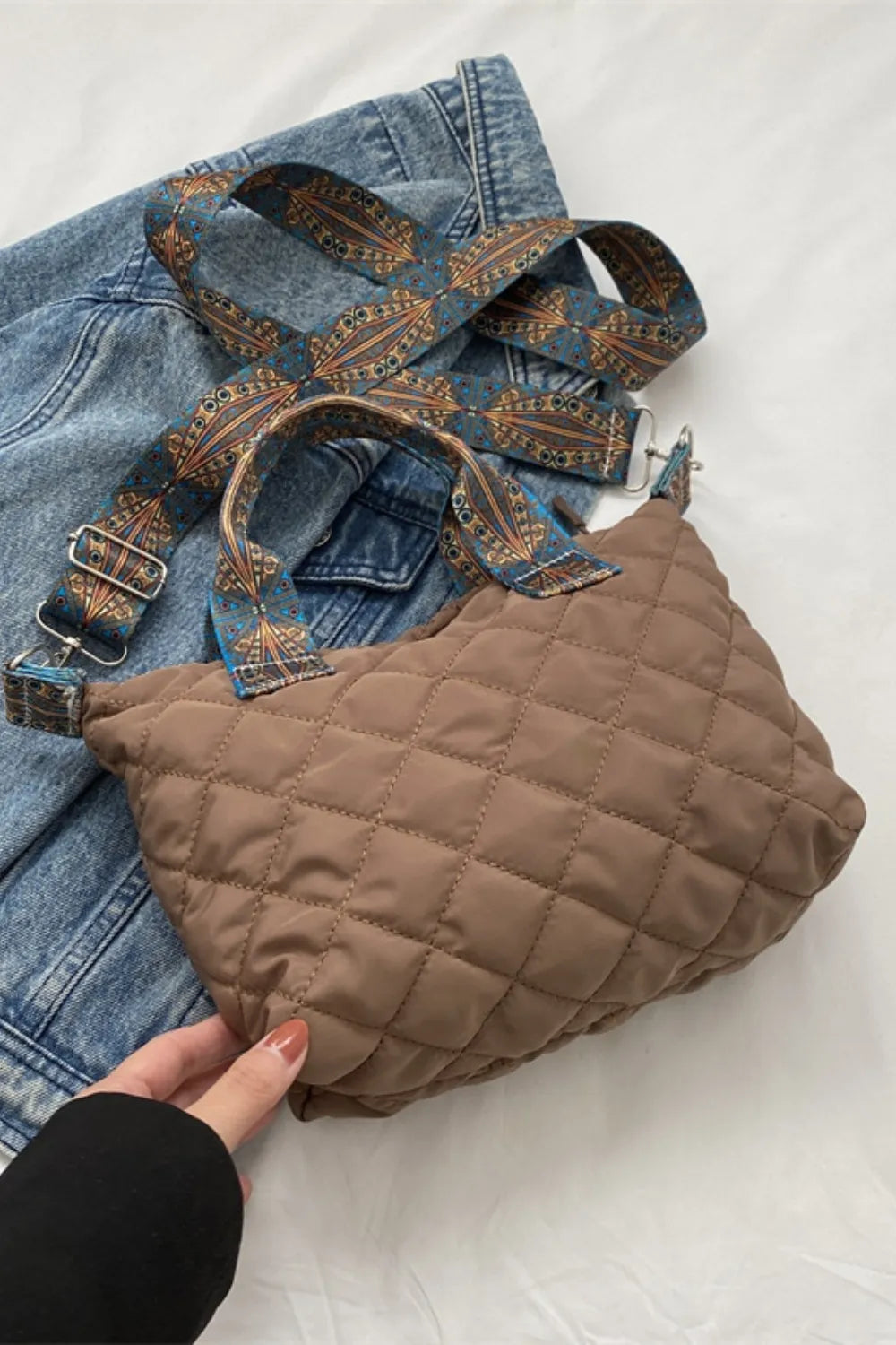 Taupe quilted satchel bag with a patterned strap and denim jacket styling.