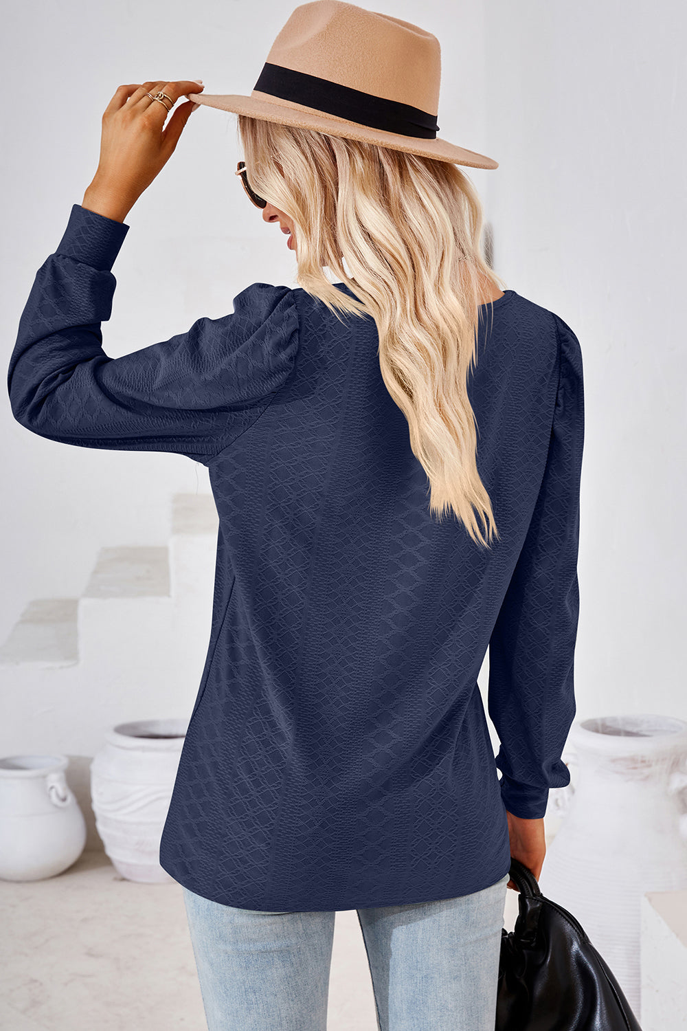 Dark blue diamond-textured puff sleeve top with a v-neckline.