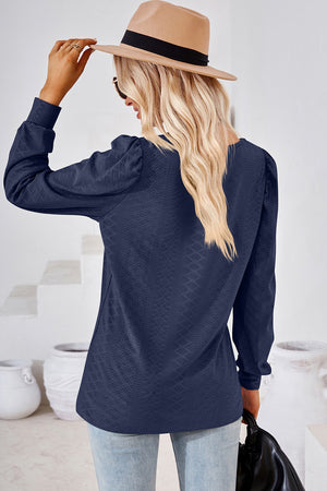 Dark blue diamond-textured puff sleeve top with a v-neckline.