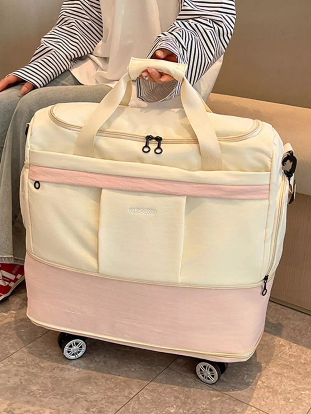 Cream and pink large rolling duffel bag with dual handles and wheels