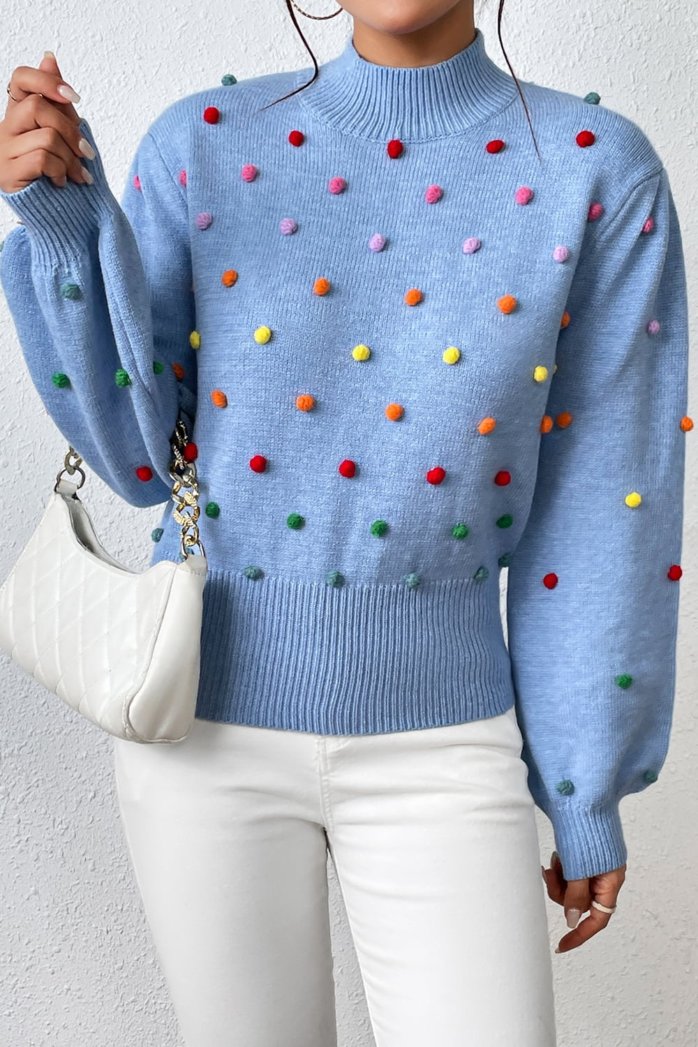 Blue blouson sweater with multicolor pom-pom embellishments and mock neck.