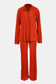 Orange-red pleated shirt and wide-leg trouser set with button front and collared neckline.