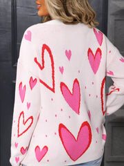 White acrylic sweater with a scattered heart pattern in pink and red, crew neck.