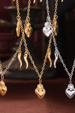 Gold and silver charm jewelry sets with sacred heart and horn pendants.
